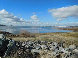 The lake at low water, riprap bank under a clouded sky courtesy of Vince Migliore&nearr; (CC BY 3.0&nearr;)