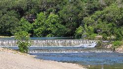 The double weir at Blue Hole spilling over clear green water below the cedar covered bluff. courtesy of Larry D. Moore&nearr; (CC BY 4.0&nearr;)