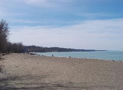 Calm water along the wooded Presque Isle shoreline courtesy of Idawriter&nearr; (CC BY-SA 3.0&nearr;)