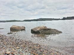 Flat water-rounded pebble at the waterline, with boulders sitting in the shallows courtesy of Augustin Liviu&nearr; (CC BY-SA 3.0&nearr;)