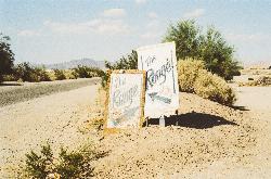 Hand-painted signs pointing the way to The Range, Slab City's open-air stage, beside the desert road courtesy of www.Pixel.la Free Stock Photos&nearr; (CC0&nearr;)