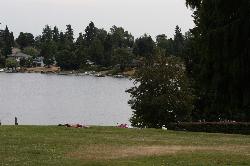Sunbathers on the grass above the shoreline, with private docks along the opposite bank courtesy of Walter Siegmund (talk)&nearr; (CC BY-SA 3.0&nearr;)