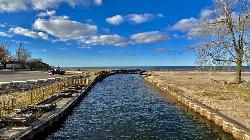 The bulkheaded channel that carries Sterling Pond into Lake Ontario, with the footbridge linking Wes courtesy of Andre Carrotflower&nearr; (CC BY-SA 4.0&nearr;)