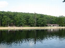 Swimmers on the sand and in the shallows, seen from the water toward the beach house and picnic shel courtesy of Ruhrfisch (talk)&nearr; (CC BY-SA 4.0&nearr;)