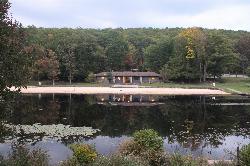 The CCC beach house and beach across dark tannin stained water on an autumn evening courtesy of Ruhrfisch&nearr; (CC BY-SA 4.0&nearr;)