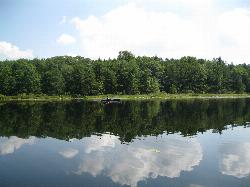 A kayaker on the open lake with the forested shoreline behind courtesy of Ruhrfisch (talk)&nearr; (CC BY-SA 4.0&nearr;)