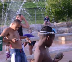 A beachgoer checks his phone in front of the fenced sprayground beside the Stephens Lake swim beach. courtesy of KOMUnews&nearr; (CC BY 2.0&nearr;)