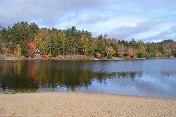 The sandy shoreline of Long Lake Town Beach and the calm water across the narrows. courtesy of Idawriter&nearr; (CC BY-SA 3.0&nearr;)