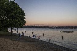 Swimmers wading off the gravel beach, with the swim platform and Lake Washington behind. courtesy of Seattle Parks&nearr; (CC BY 2.0&nearr;)