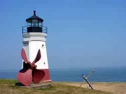 The lighthouse with a ship propeller and anchor on the lawn above the beach. courtesy of Unknown authorUnknown author or not provided&nearr; (Public domain&nearr;)