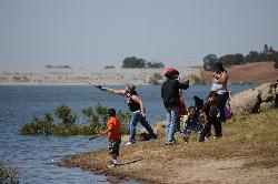 Families fishing from the Hensley Lake shoreline, with the Hidden Dam embankment across the water. courtesy of U.S. Army Corps of Engineers Sacramento District&nearr; (Public domain&nearr;)