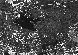 1974 aerial view of Lincoln Woods State Park showing the dark expanse of Olney Pond surrounded by th