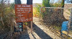BLM pool area rules sign beside the chain-link fence around the soaking tubs, with the blue tub visi courtesy of blmcalifornia&nearr; (Public domain&nearr;)