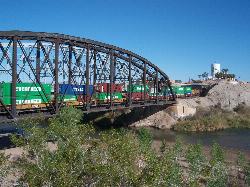 A freight train crosses the railroad bridge above the Colorado River and its sandy bank at Gateway P courtesy of XeresNelro&nearr; (CC BY-SA 4.0&nearr;)
