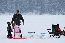 A volunteer with young anglers on the ice at Lion Lake during the Canyon Kid's Christmas Fund fishin courtesy of Forest Service Northern Region from Missoula, MT, USA&nearr; (Public domain&nearr;)